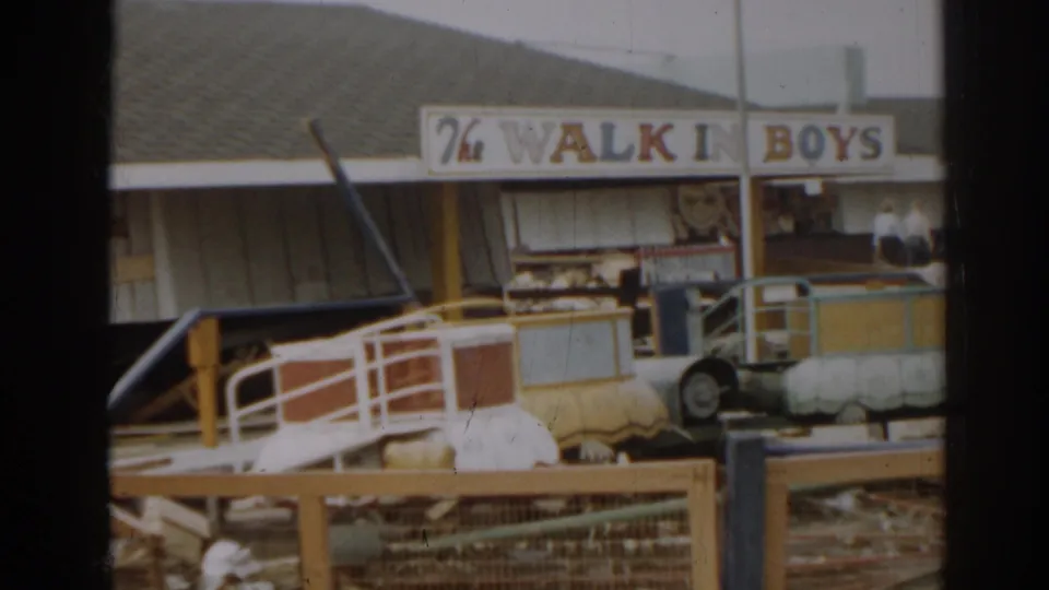 1963 New Jersey footage showing a damaged amusement or boardwalk ride area beneath a painted walk-in sign.