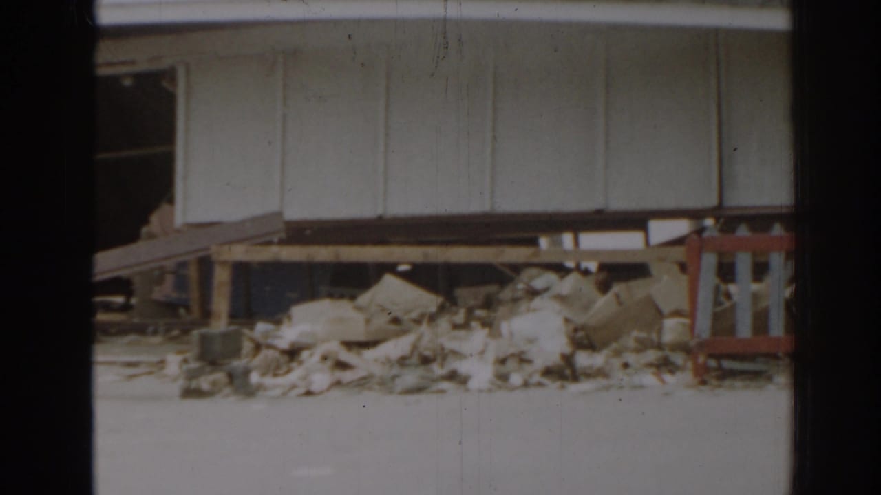White building wall above a pile of rubble and broken materials.
