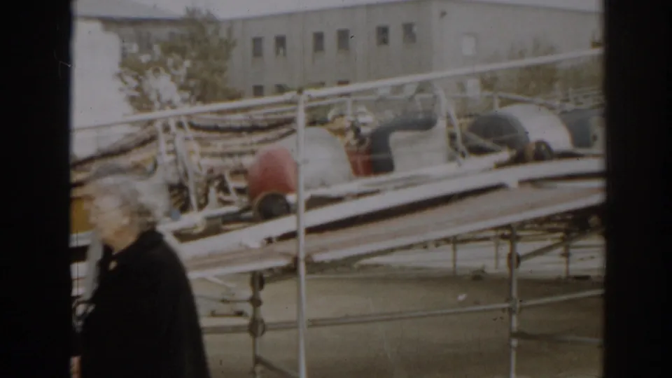 1963 New Jersey 8mm frame showing a man in dark clothing near damaged boats, railings, and scattered storm debris.