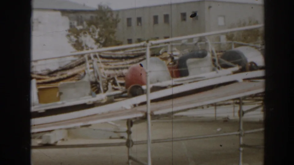 1963 New Jersey 8mm frame showing damaged boat hulls, bent railings, and debris along a coastal storm aftermath scene.