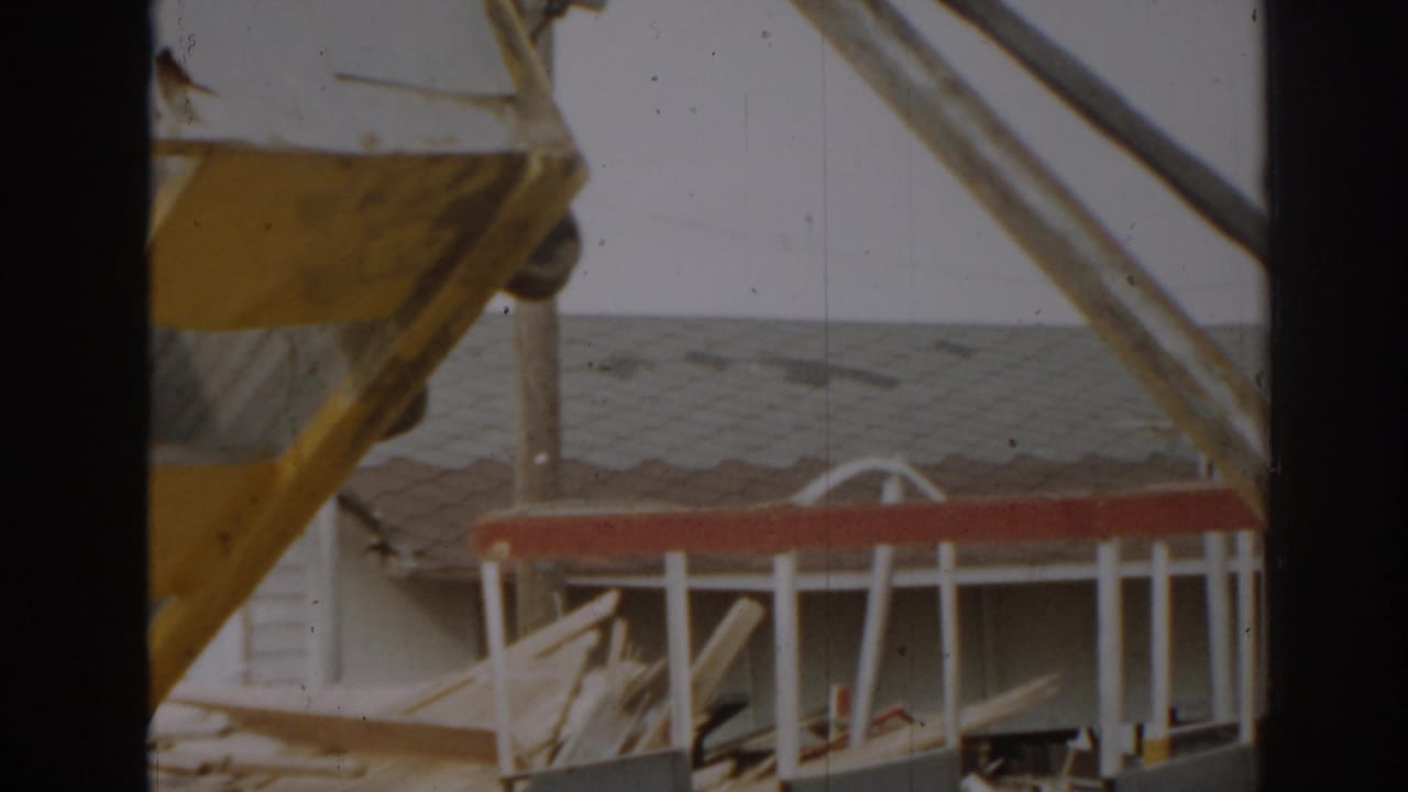 Yellow metal framework and scattered debris beside a low roofline.