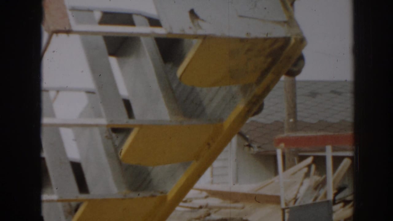 Close view of white and yellow metal framework with debris behind it.