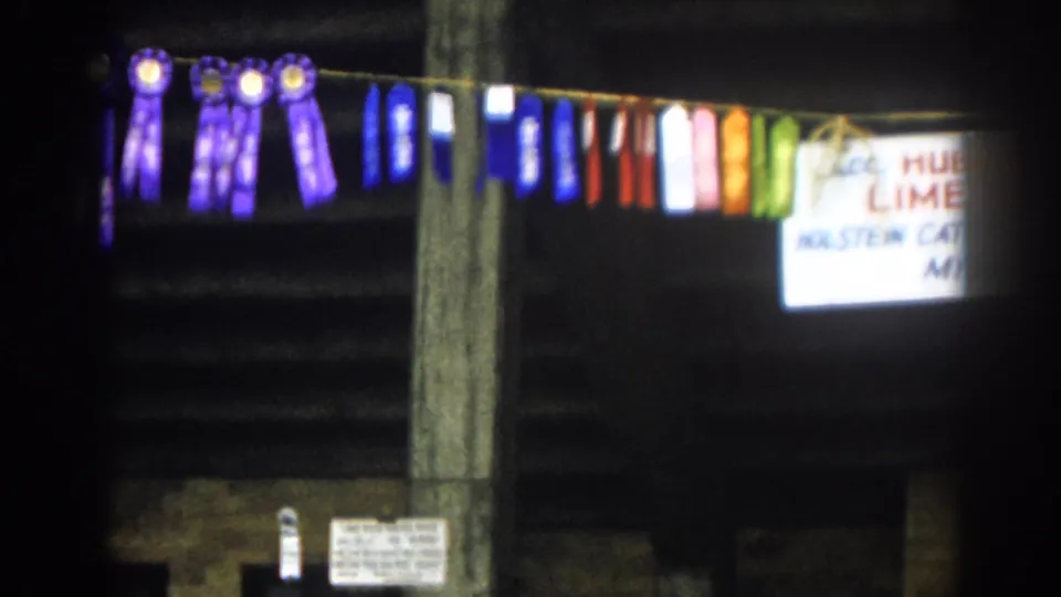 1963 8mm frame showing purple, blue, red, white, and green ribbons near a partially visible Hubert S. Miller Lime Rock Farm sign.