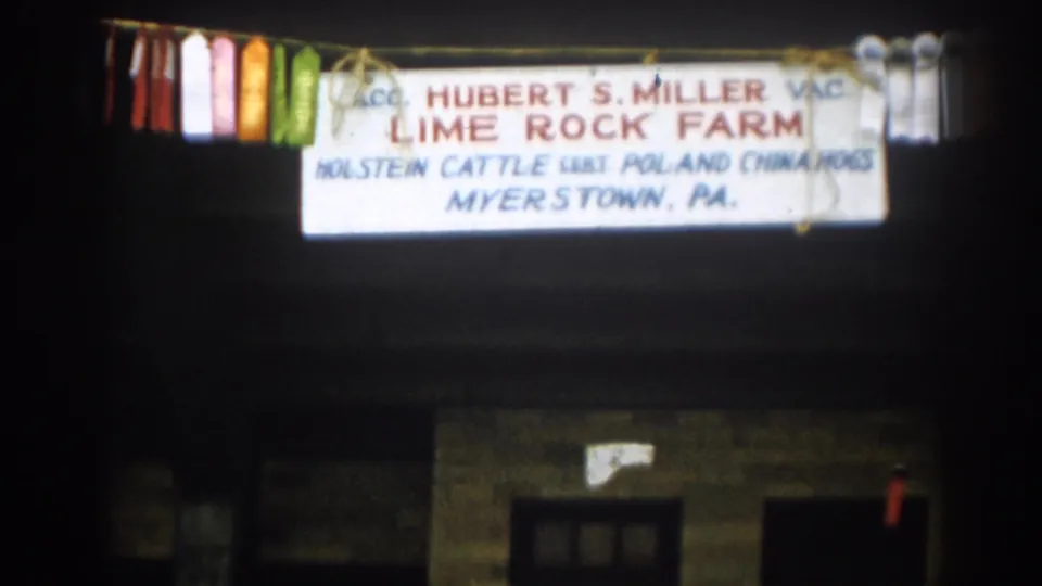 1963 8mm frame of an illuminated Lime Rock Farm sign reading Hubert S. Miller and Myerstown, PA, with ribbons at both sides.