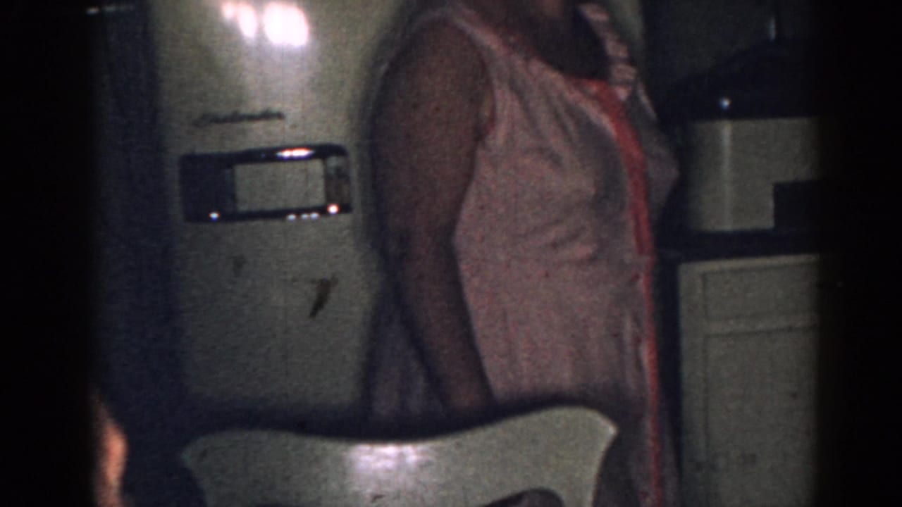Woman cropped at the side of a refrigerator with a chair back in front.