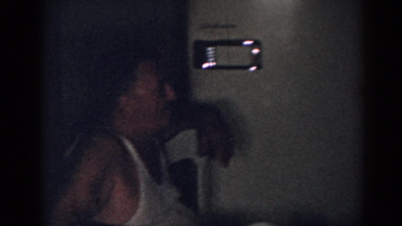 Dim kitchen scene with a man in glasses near a woman in a light apron.
