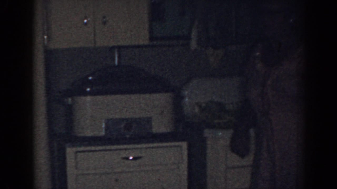 Dim kitchen counter with cabinets, sink area, and a partially visible person at right.
