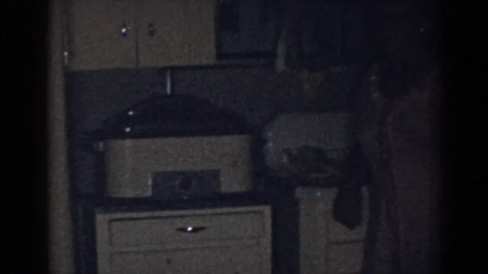 1963 New Jersey kitchen interior with cabinets, counter appliances, sink area, and a partially visible adult at the edge of frame.