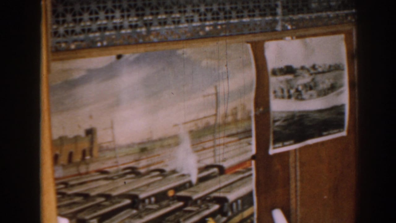 Wood-paneled wall with a rail-themed painting and pinned black-and-white photographs.