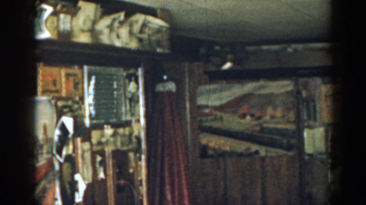 Interior wall with shelves, framed pictures, a red curtain, and a train mural on the right.