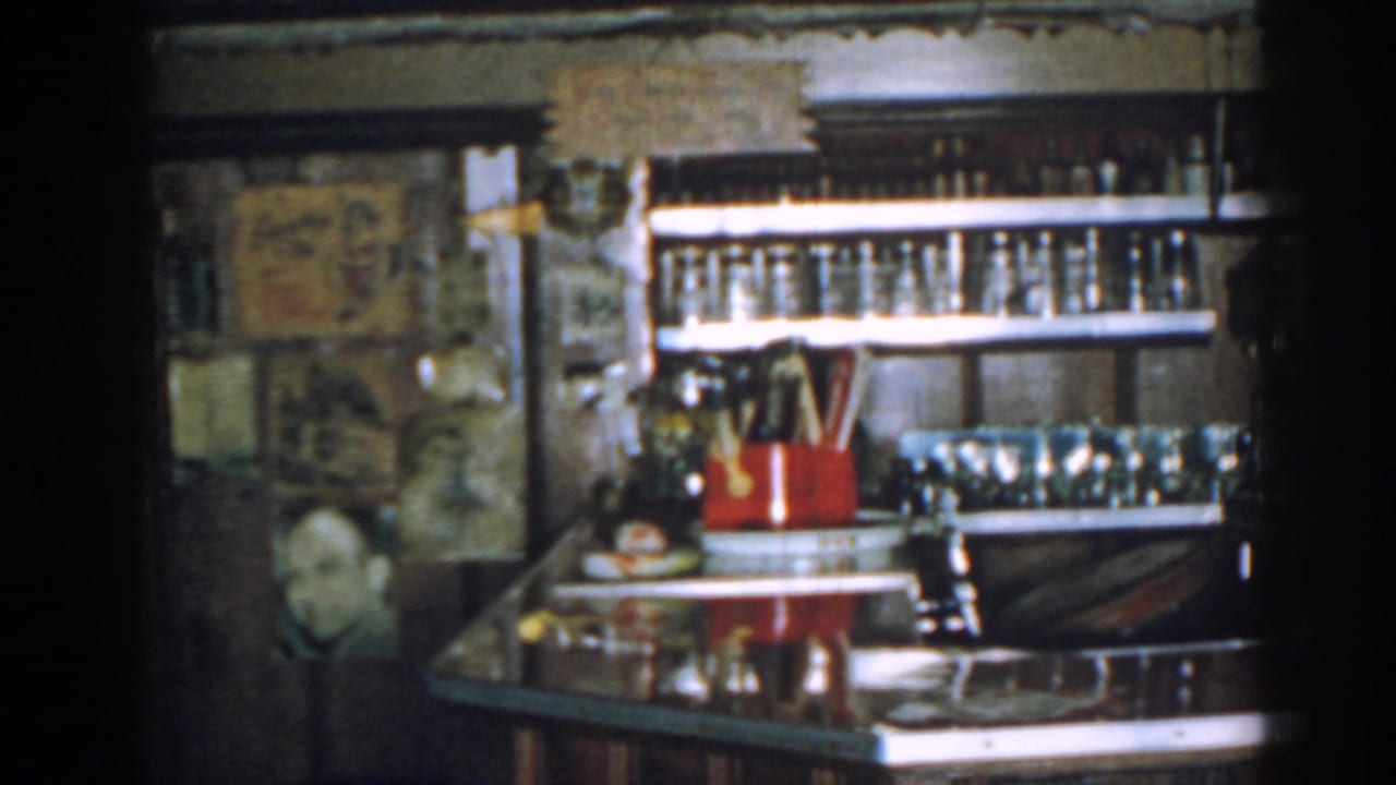 Vintage bar counter with bottle shelves, glassware, and a red utensil holder.