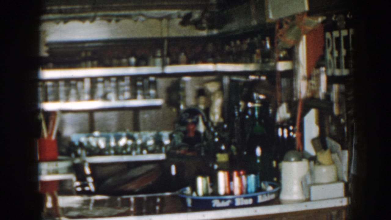 Interior counter with bottle shelves, glassware, jugs, a blue tray, and part of a BEER sign on the wall.
