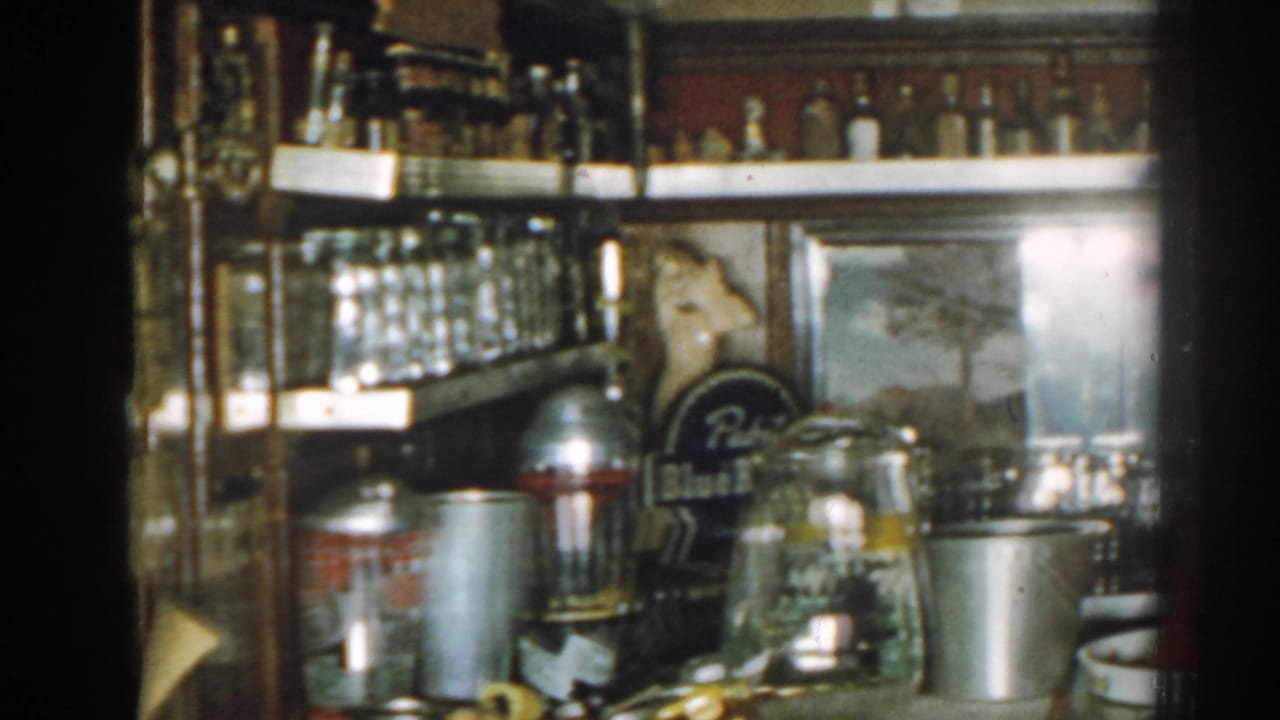 Bar shelves with glassware, bottles, metal containers, and a Pabst Blue Ribbon sign.