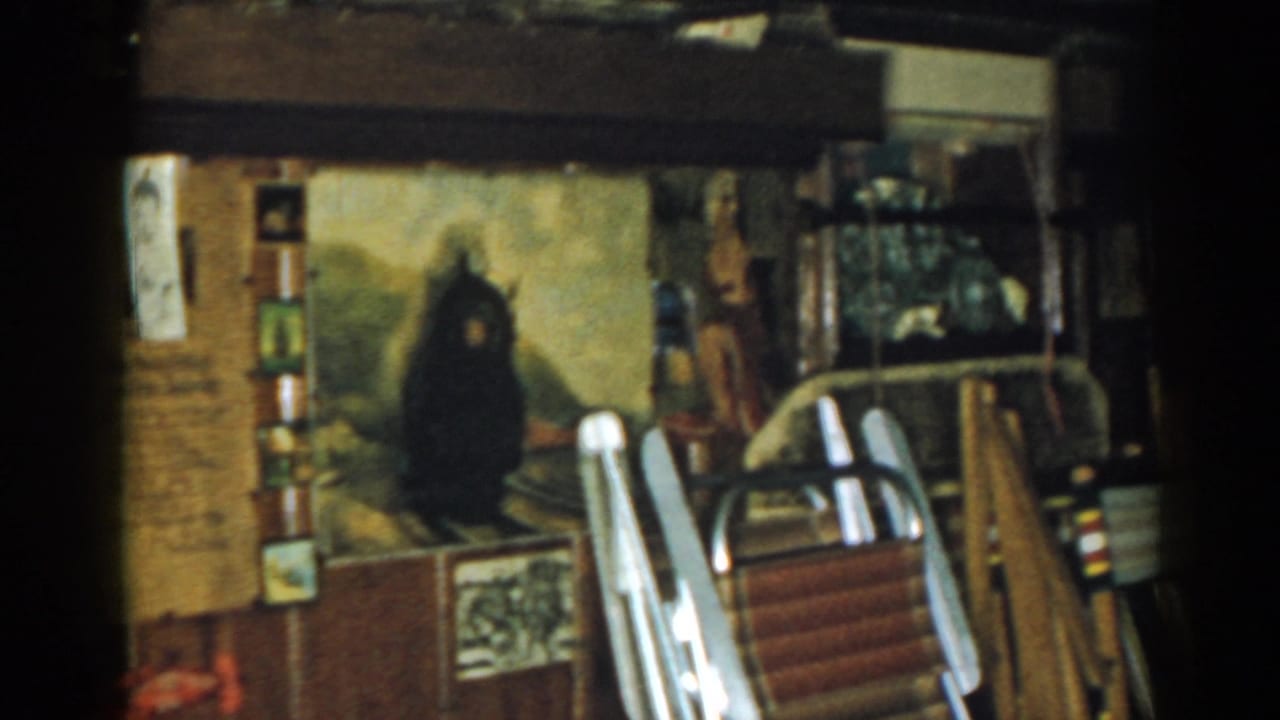 Storage-room wall with a large painting, stacked folding chairs, papers, and a window area.