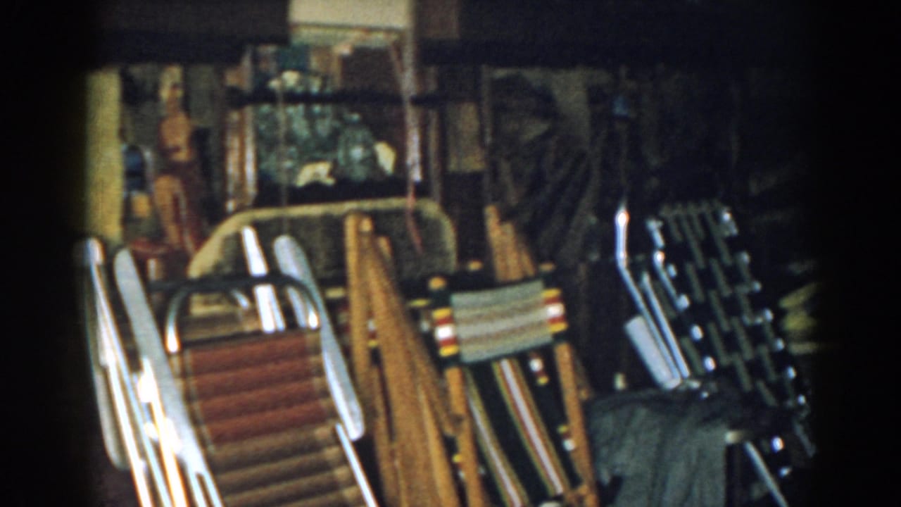 Dim basement corner with stacked folding chairs and household items.