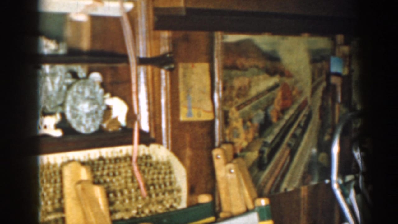 1963 New Jersey basement view with shelves, a wicker basket, record player, folding chairs, and a painted train mural.