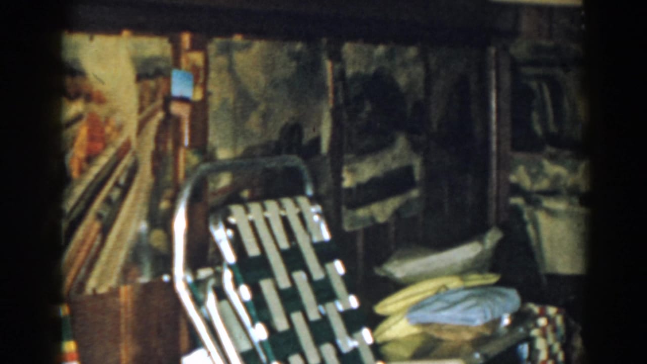 Living room corner with folded chair, cushions, furniture, and partial view of a birdcage.