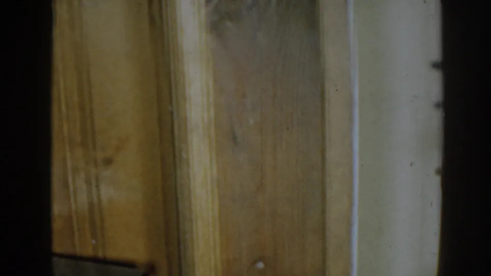 1963 New Jersey 8mm frame showing a close, soft-focus view of wood wall paneling, trim, and shadowed interior edge.