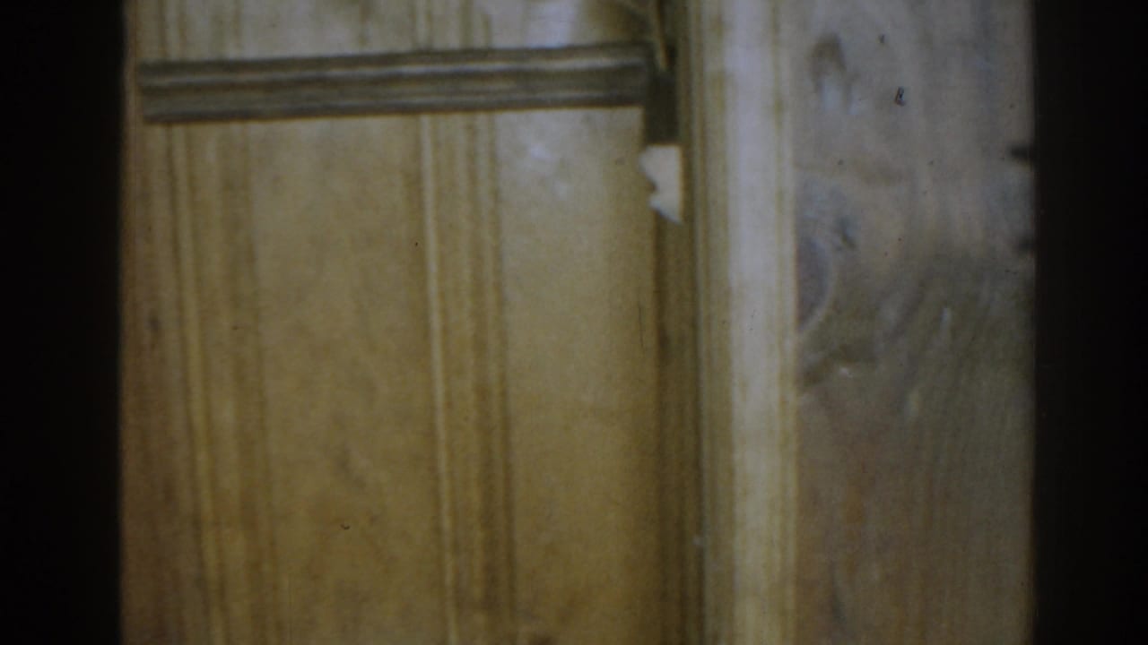 Wood paneling with trim and part of a small shelf or frame near the upper right.