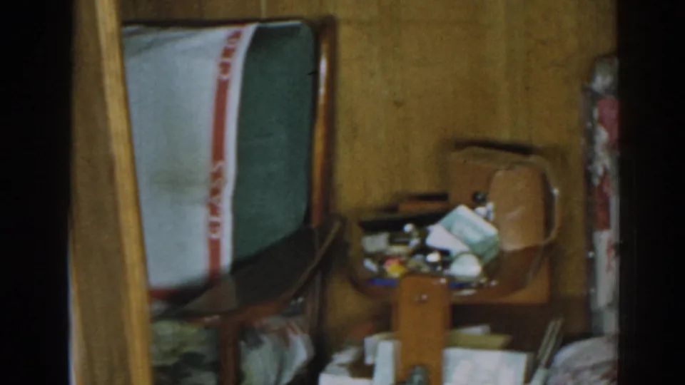 1963 New Jersey interior with a suitcase, bedding, wood paneling, and small household items clustered in a messy corner.