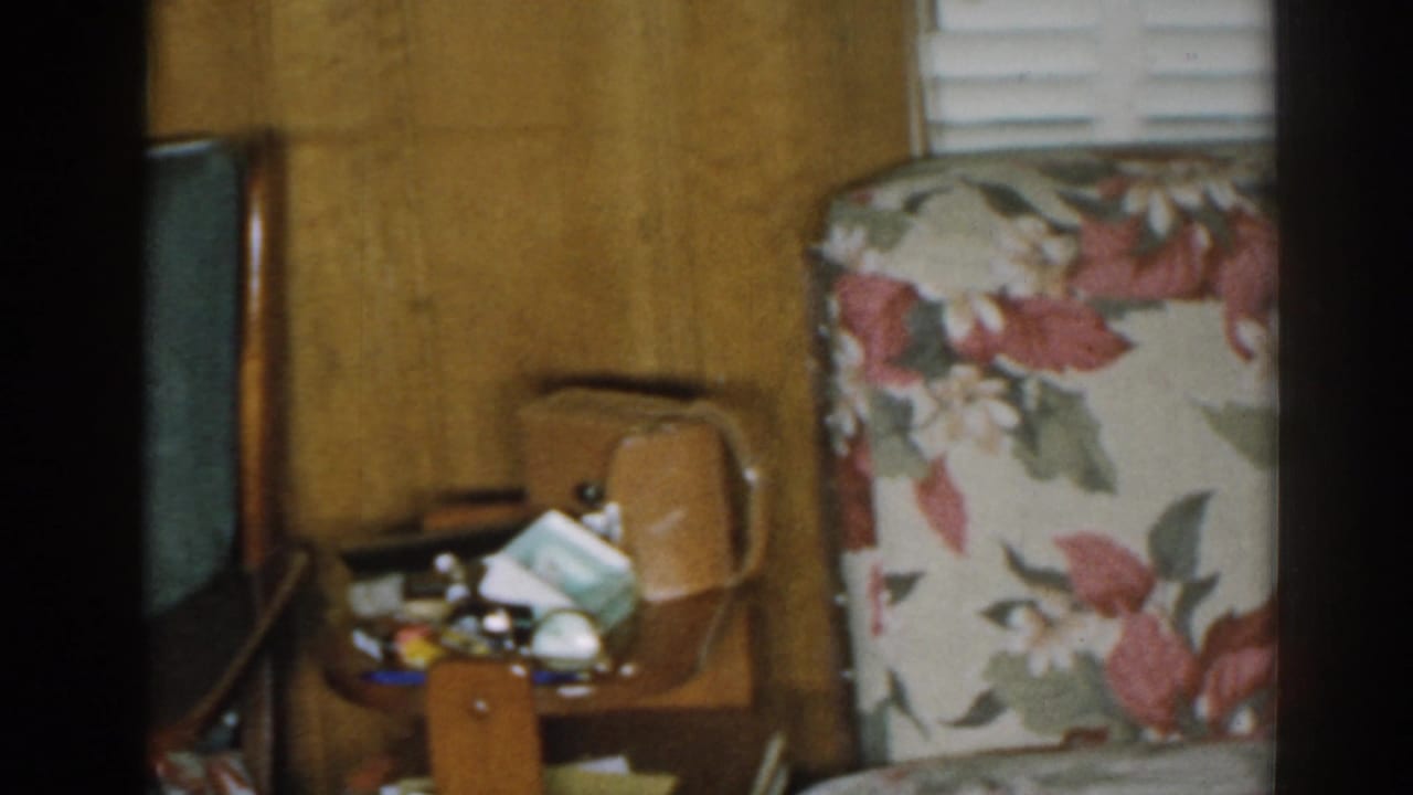 1963 New Jersey interior with floral upholstery, a small side table of personal items, a wooden chair, and wood paneling.