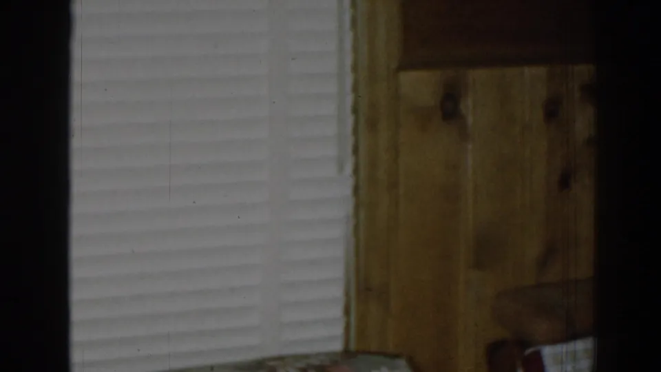A 1963 New Jersey interior frame shows white blinds, wood paneling, and a partial floral couch at the lower edge.