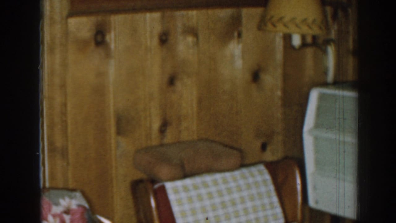 1963 New Jersey living-room detail with knotty wood paneling, an armchair, a wall lamp, and a white air-conditioning unit.