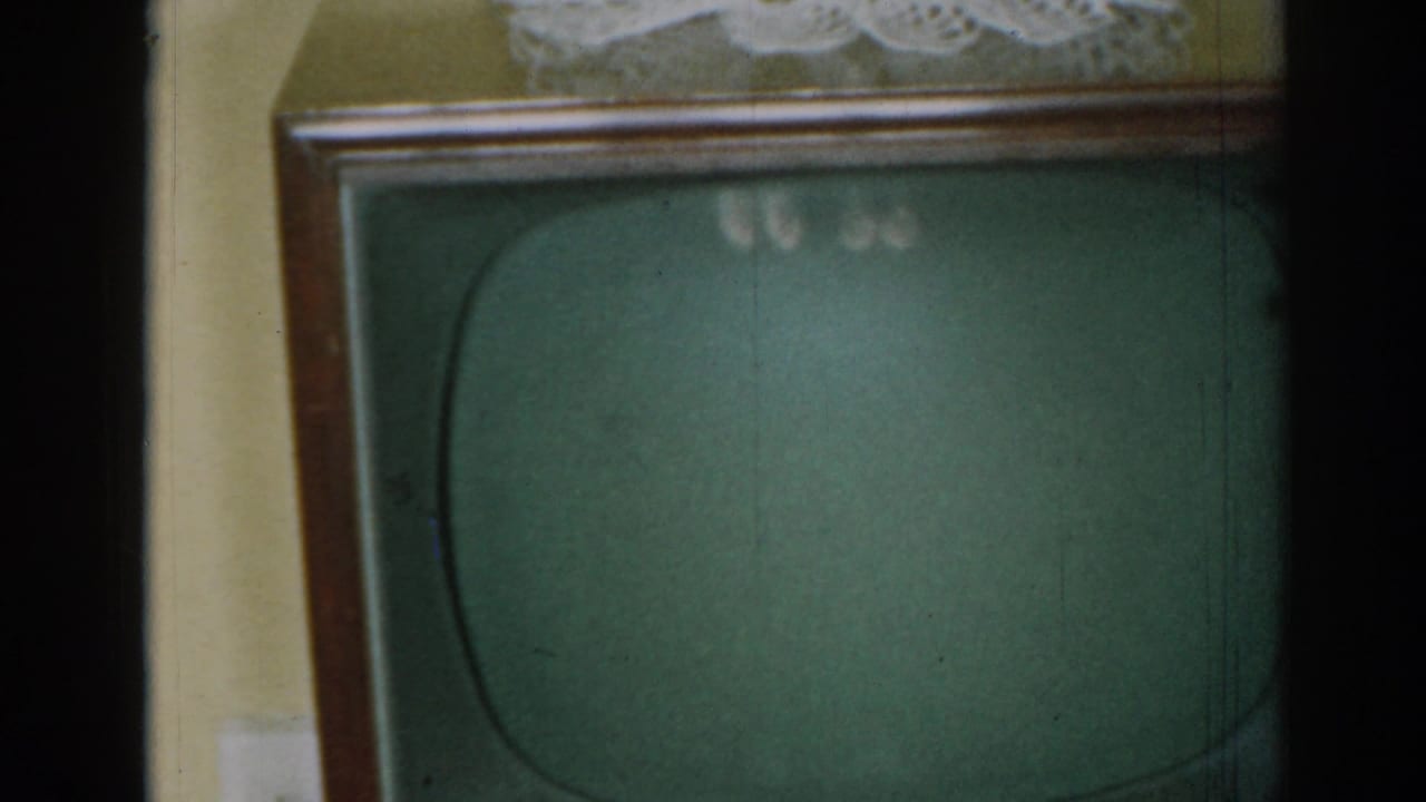 Wood-framed television with green screen and lace doily in a living room.