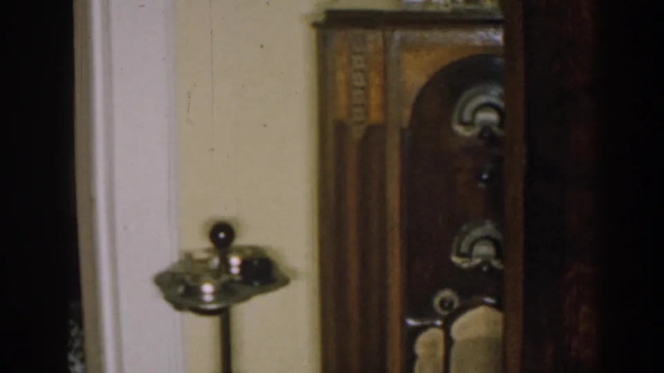 1963 New Jersey interior detail showing a carved dark wood cabinet with an arched door and small household objects on top.