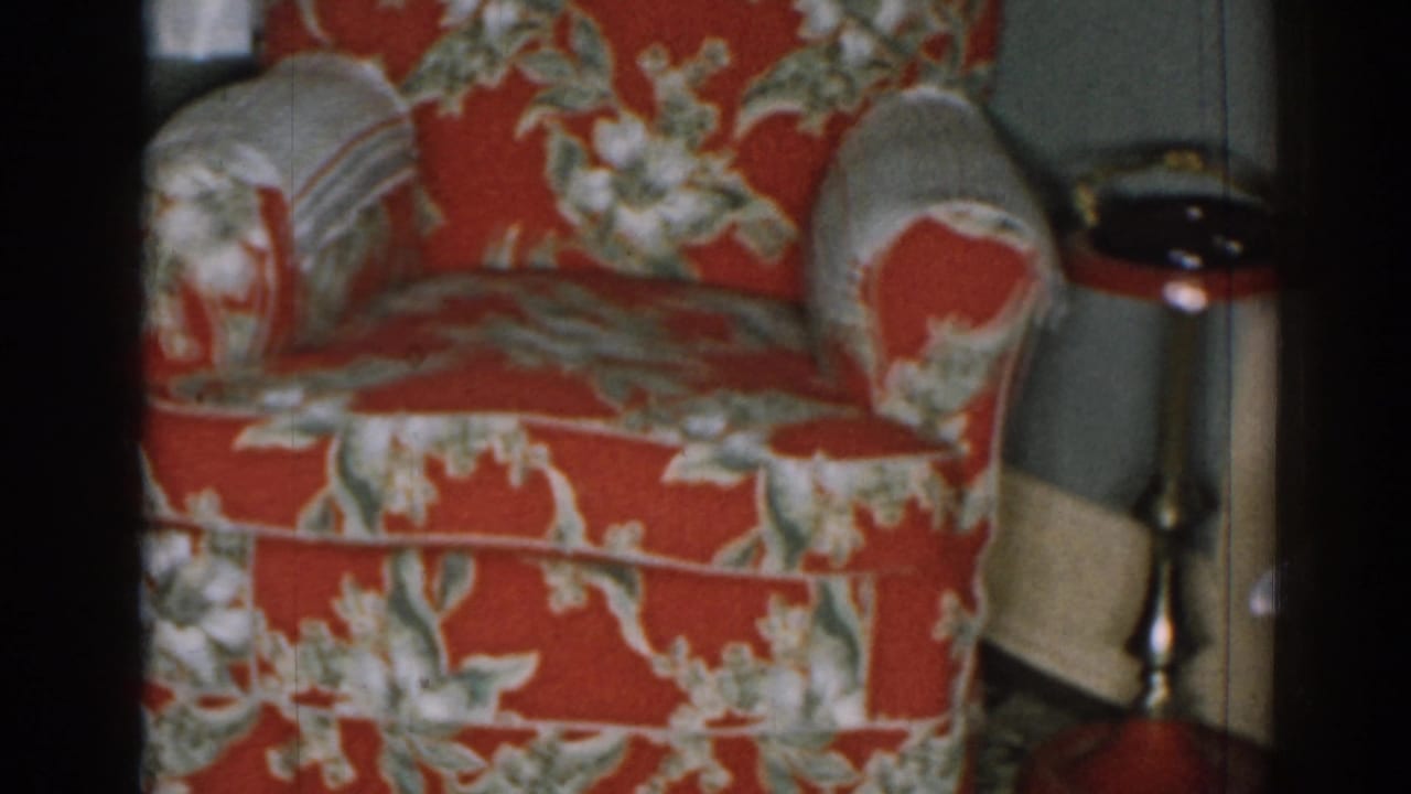 Red floral armchair beside a small dark-topped side table in a living room.