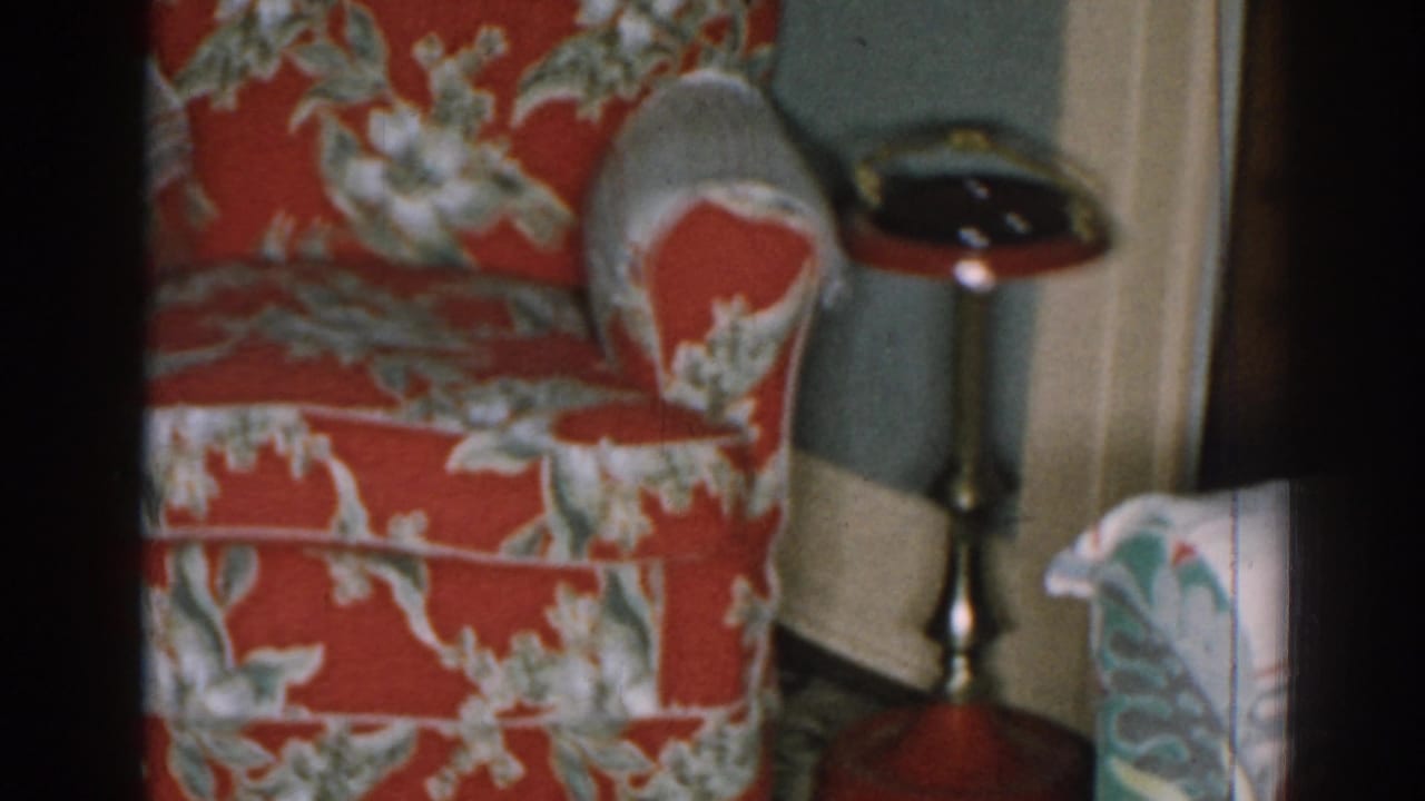 Red floral armchair with a small pedestal side table near a doorway.