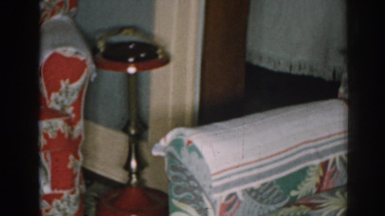 Floral armchair beside a red-topped standing ashtray in a living room corner.