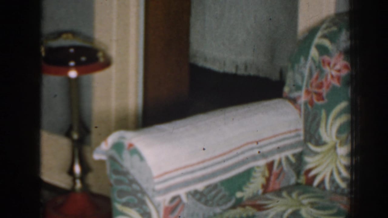 Close view of a floral armchair arm with a standing ashtray in the background.