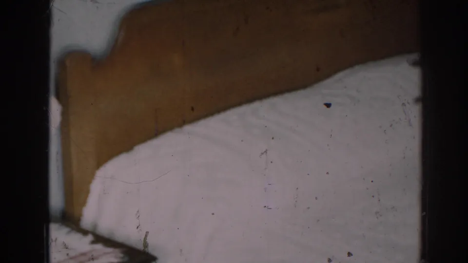 1963 New Jersey bedroom frame focused on the wooden headboard and white bedding, with soft focus and film wear visible.