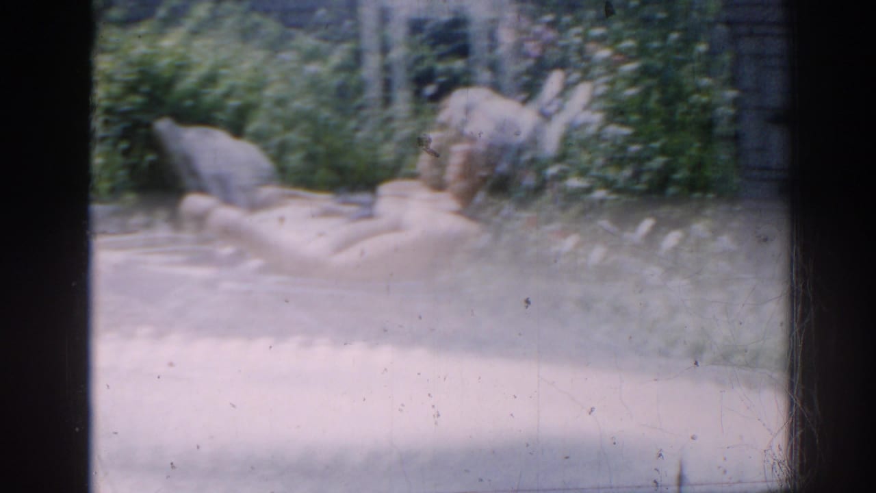 Shirtless older man reclining on a lounge chair outdoors in bright sun.