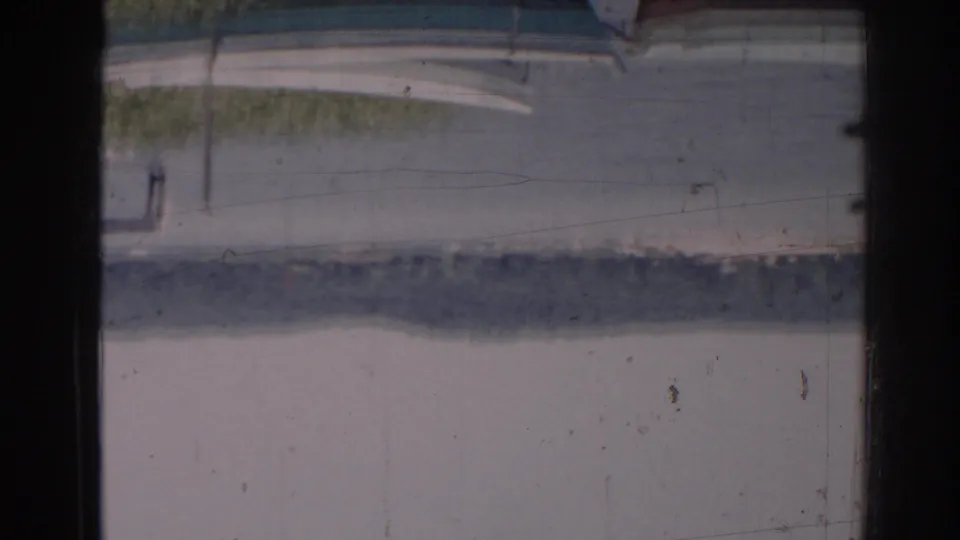 Soft, blurry 8mm view through dark window mullions toward an indistinct outdoor surface and foliage.