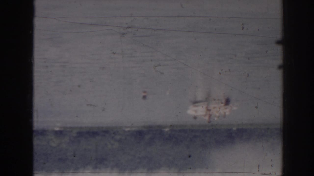 Damaged 8mm frame with scratches, dust, and dark vertical borders.