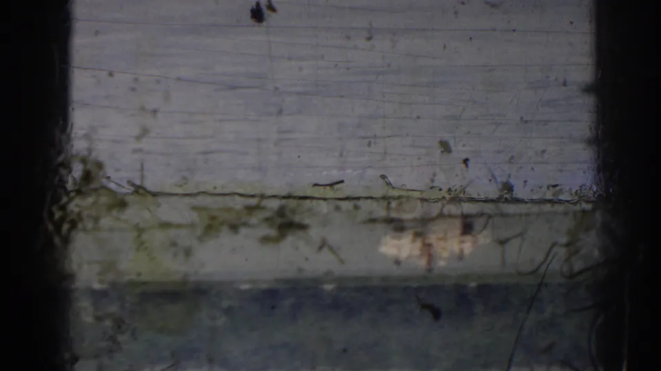 Damaged 1963 New Jersey 8mm frame with a central dark obstruction, scratches, dust, and a faint outdoor background.