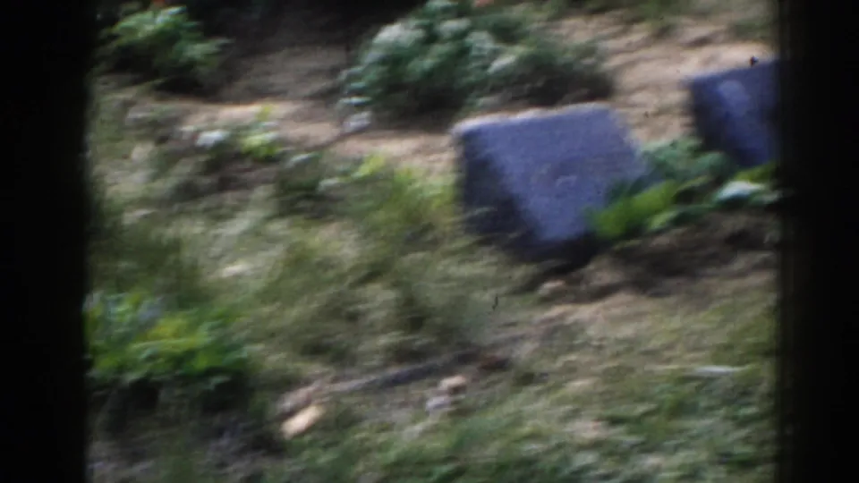 1963 New Jersey 8mm frame showing soft, handheld views of grey cemetery markers, grass, and low plantings.