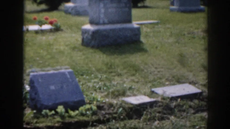 1963 New Jersey cemetery frame with an upright monument base, low grave plaques, grass, flowers, and additional headstones in the background.