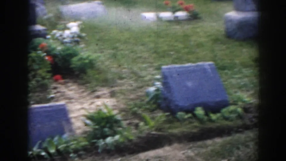 1963 New Jersey 8mm cemetery view showing low grave markers, a flower bed, grass, and soft handheld framing.