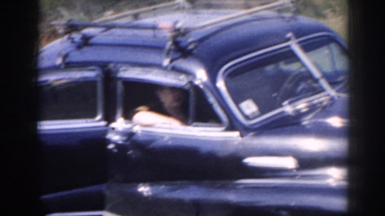 Dark blue vintage sedan with chrome trim and roof rack seen from the side.