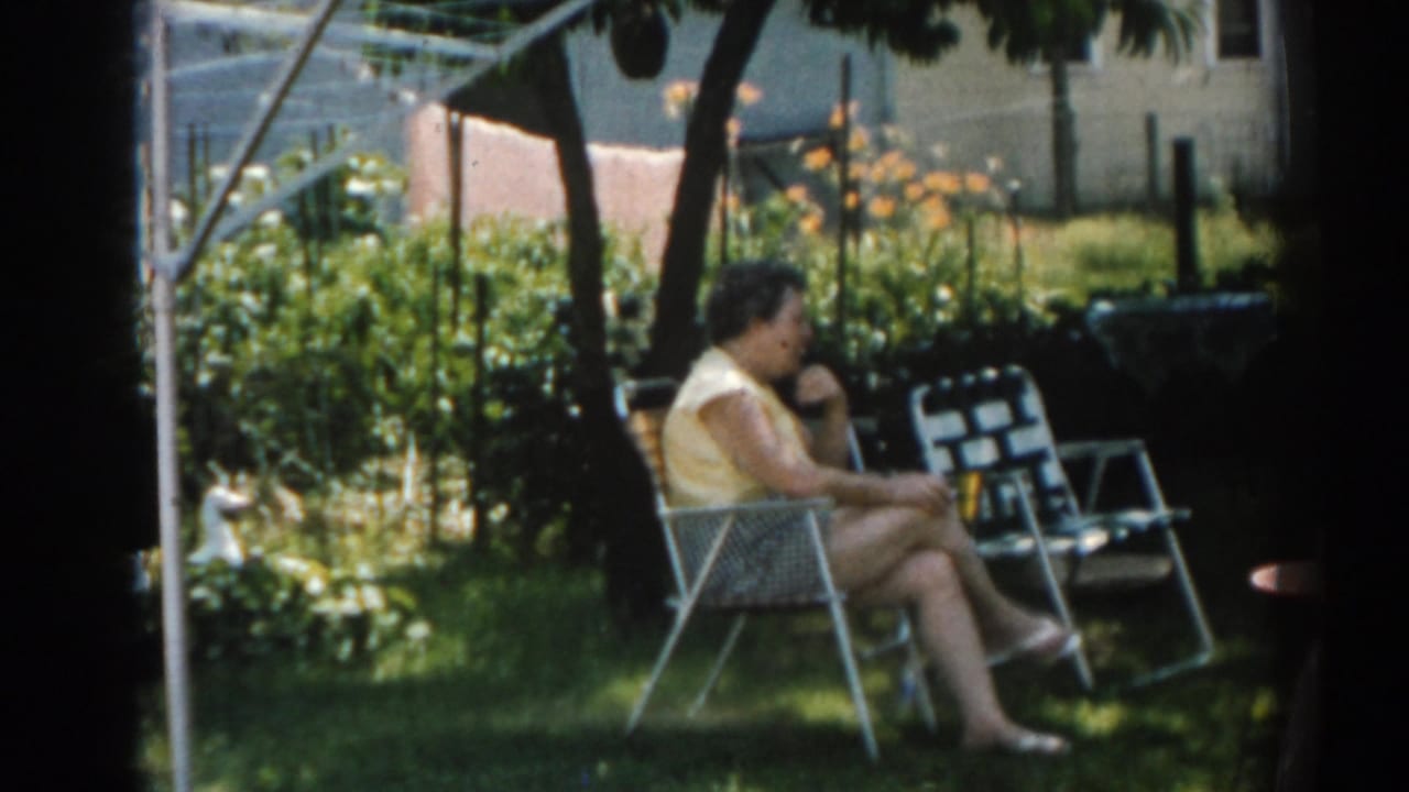 Women seated in folding lawn chairs on a shaded backyard lawn.