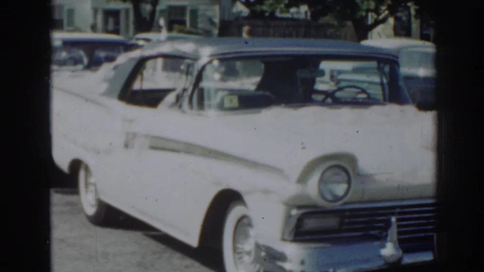 1963 New Jersey street view of a white American sedan with chrome details parked near another vehicle.