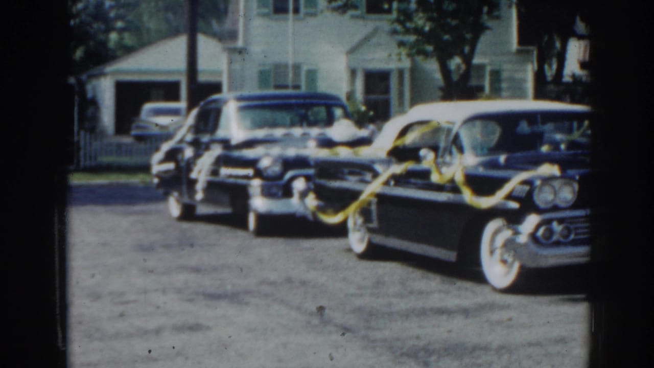 Two dark decorated cars parked near a house and garage.