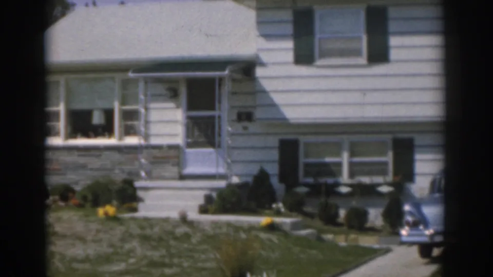 1963 New Jersey 8mm frame with a closer handheld view of the suburban house, front steps, lower windows, lawn, and car edge.