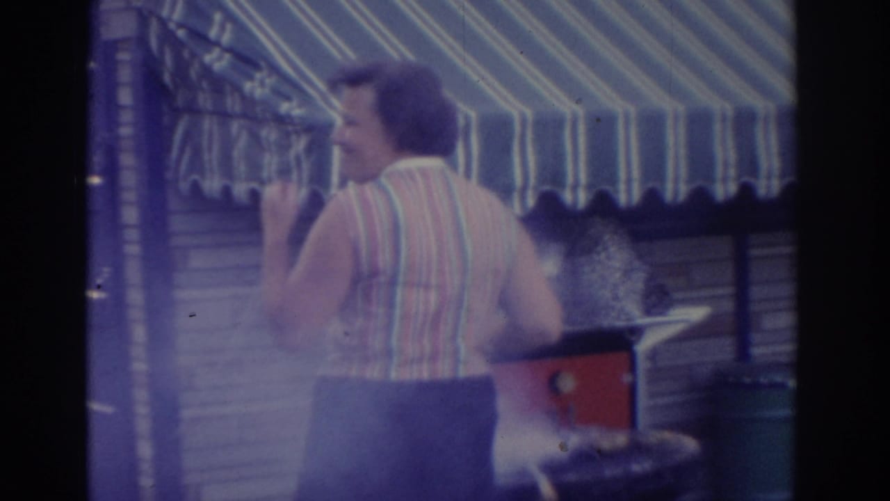 Woman in a striped sleeveless top near a smoking barbecue grill under a striped awning.