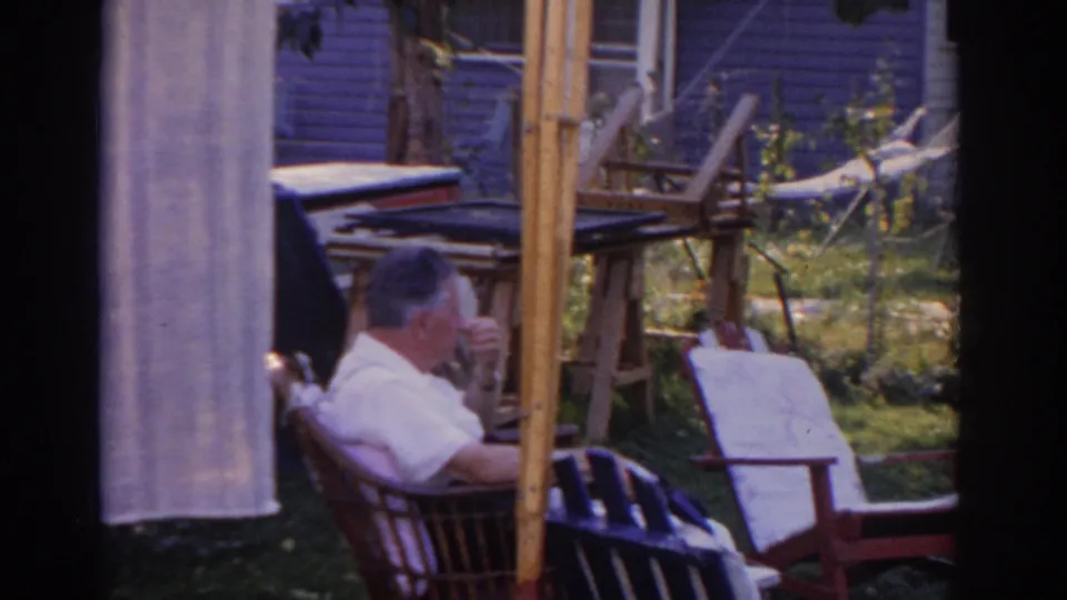 A New Jersey backyard view shows the man seated near a hammock, hanging cloth, chairs, and house siding.