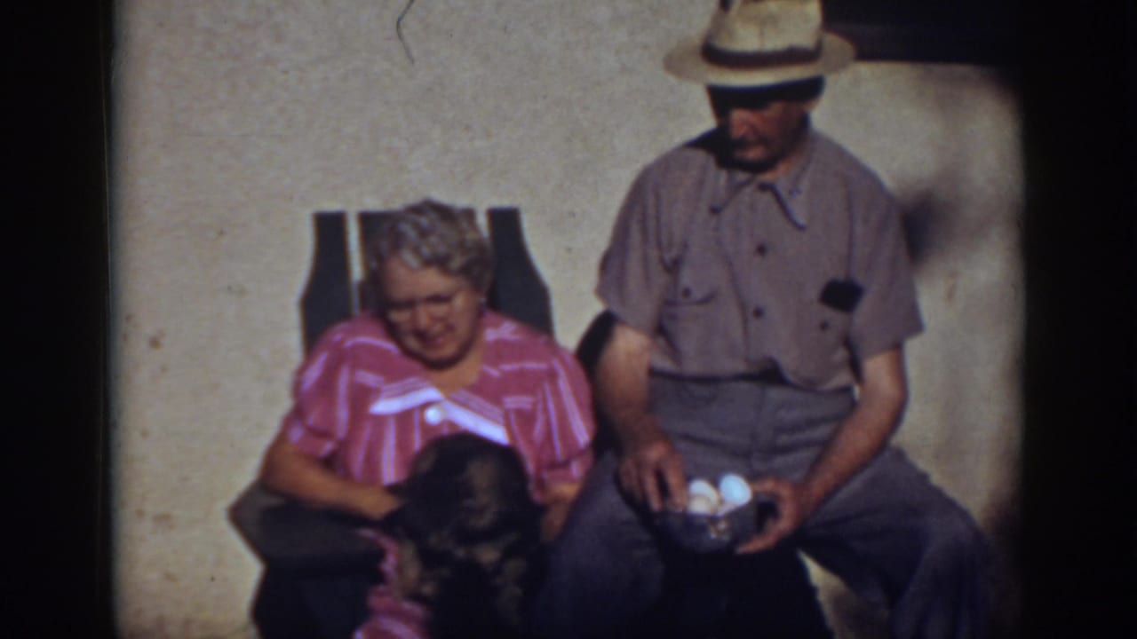 Woman pets a small dog on her lap while the seated man beside her holds a bowl containing eggs.