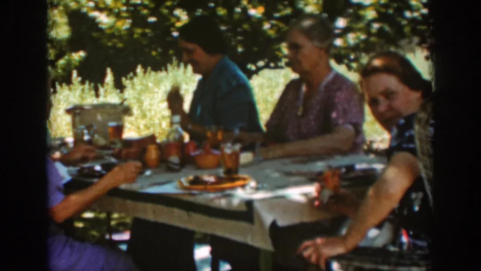 A 1939 Auburn picnic scene shows women seated beneath trees, with tableware and drinks spread across a white cloth.